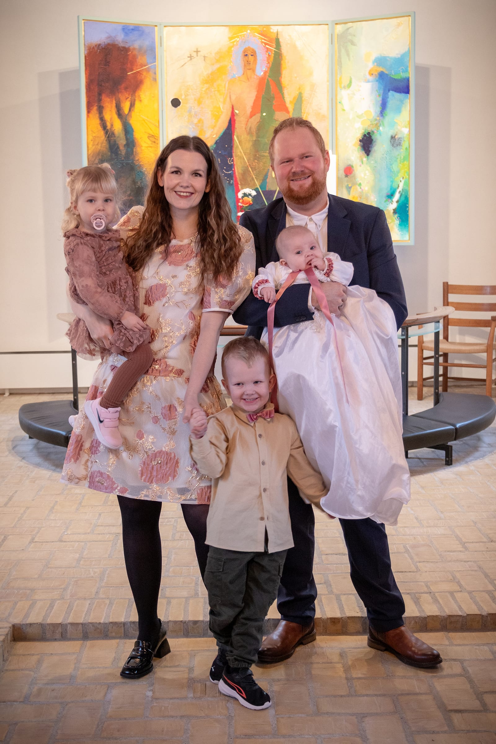 Familie på fem til barnedåb med baby i dåbskjole i kirke