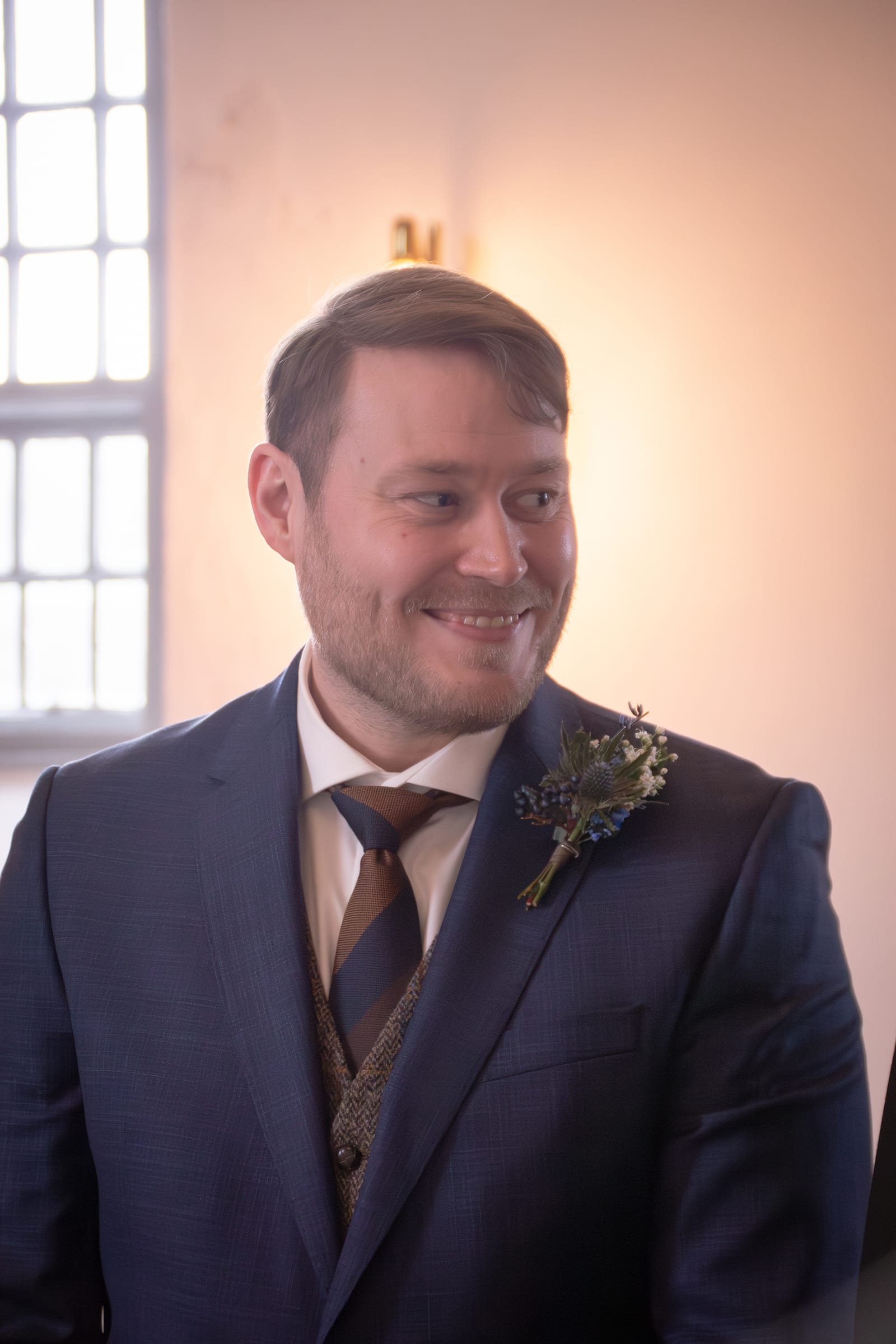 Portræt af gom i mørkeblåt jakkesæt med boutonniere i kirke