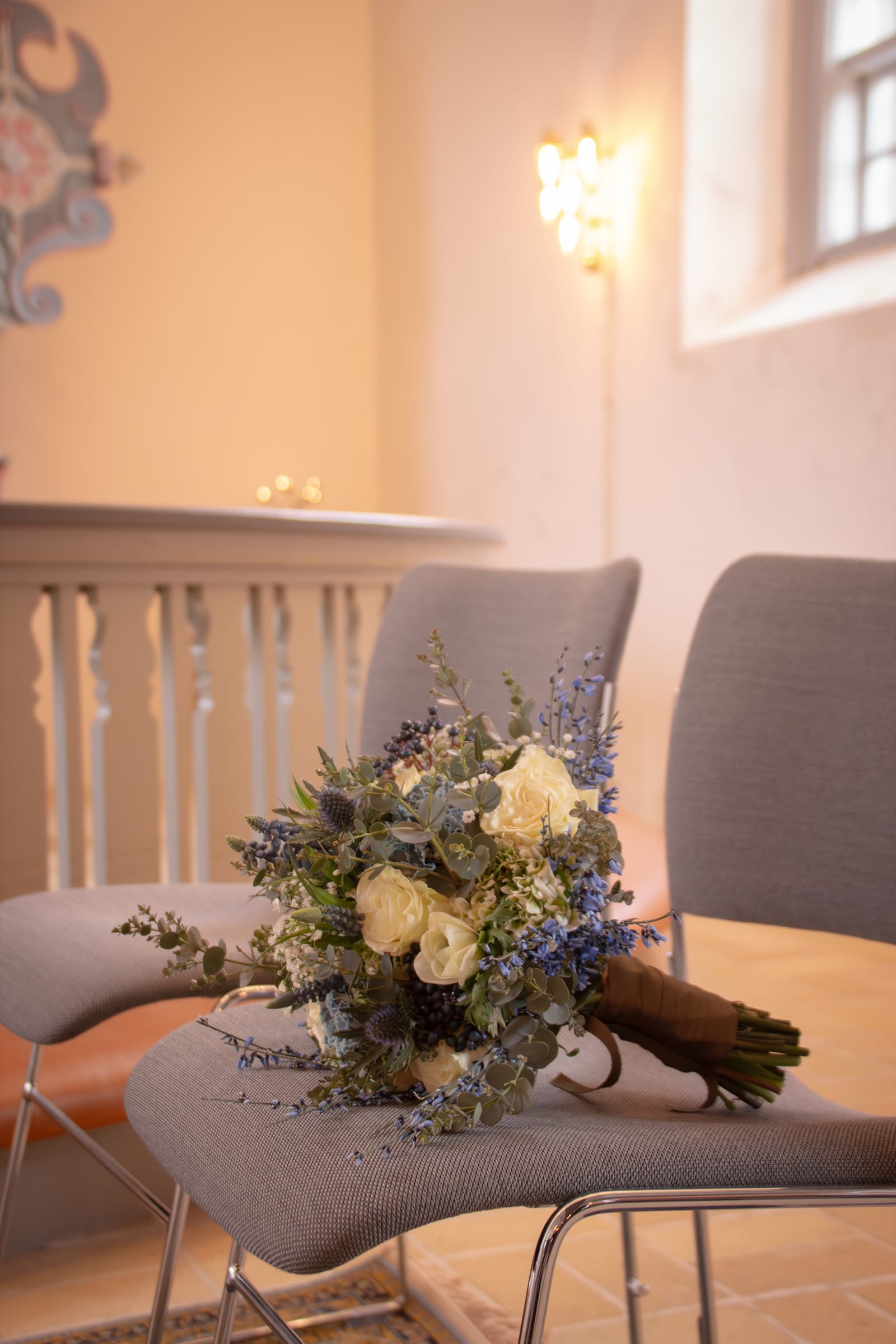 Brudebuket med blå og hvide blomster ligger på stol i kirke