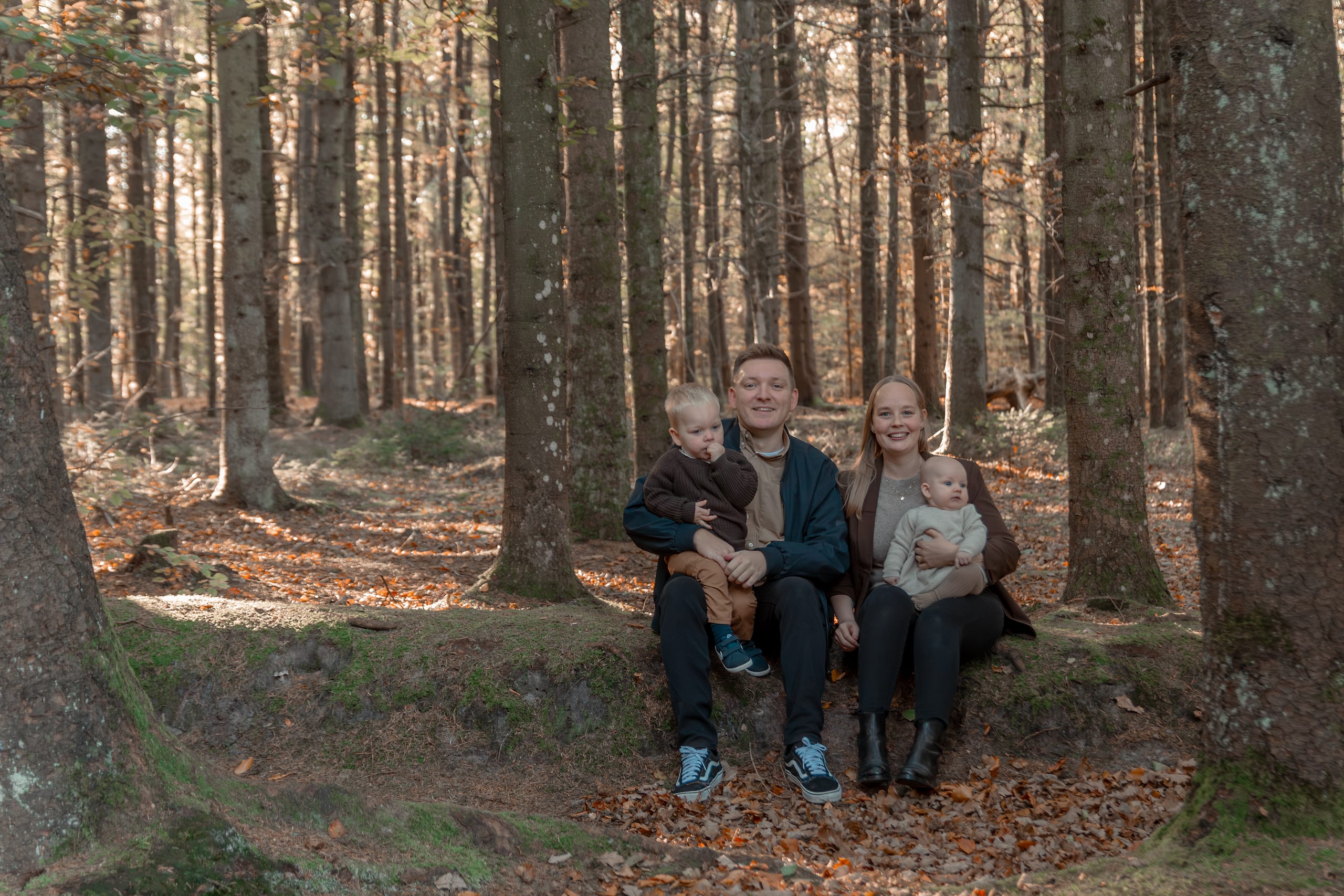 Familie på fire sidder sammen i efterårsskov ved Ikast