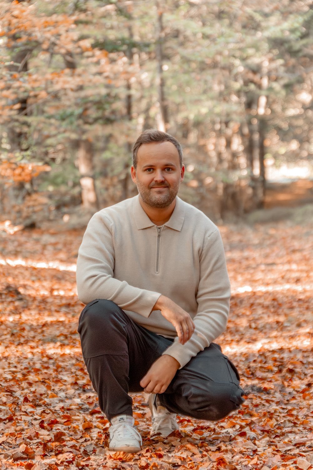 Fotograf Rasmus Birk Knudsen sidder på hug i efterårsskov ved Ikast