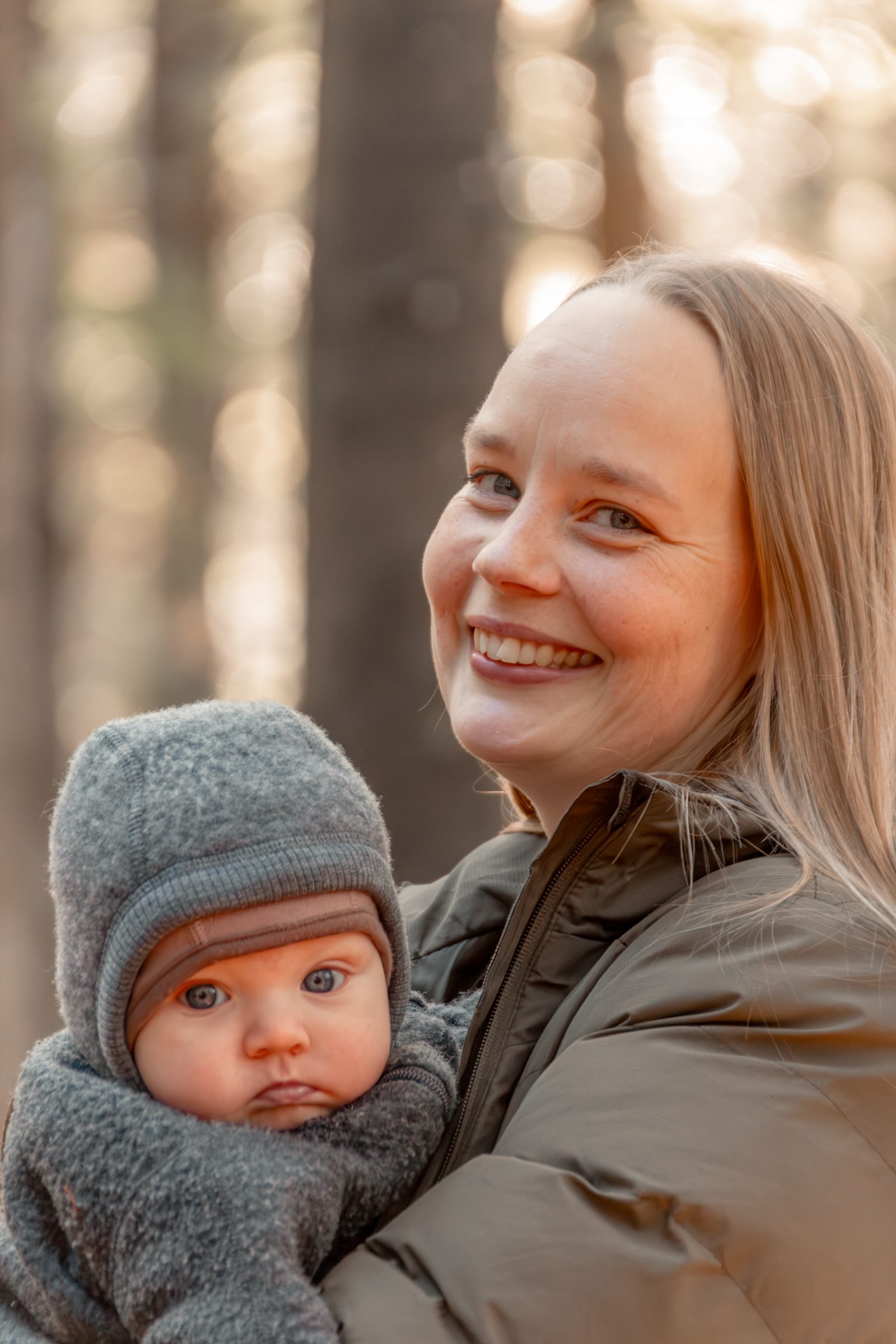 Ung kvinde med lille barn på armen i efterårsskov